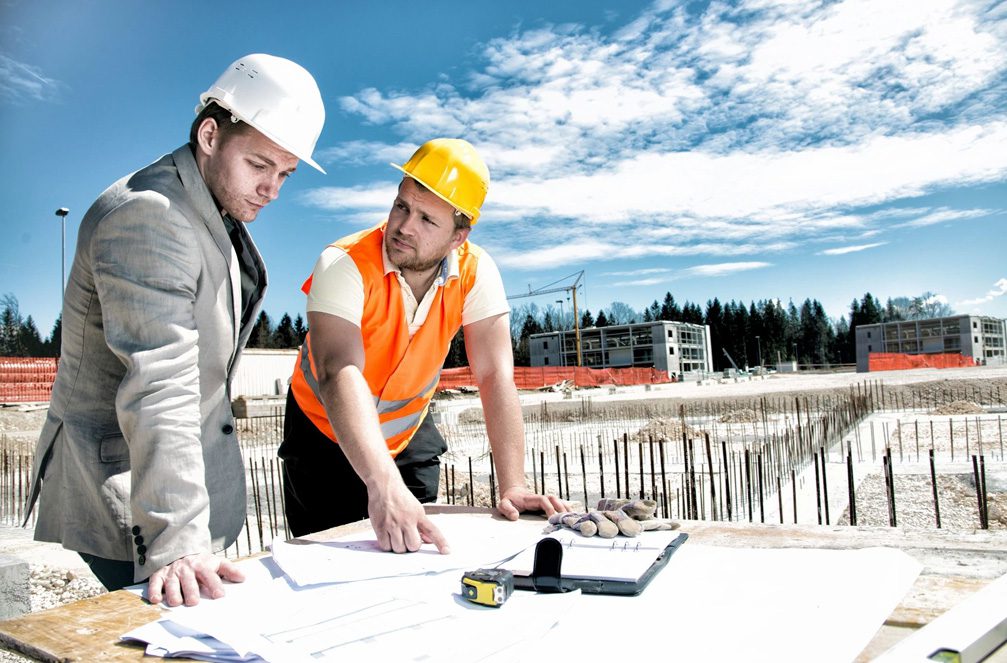 Two men in hard hats looking at a construction plan.